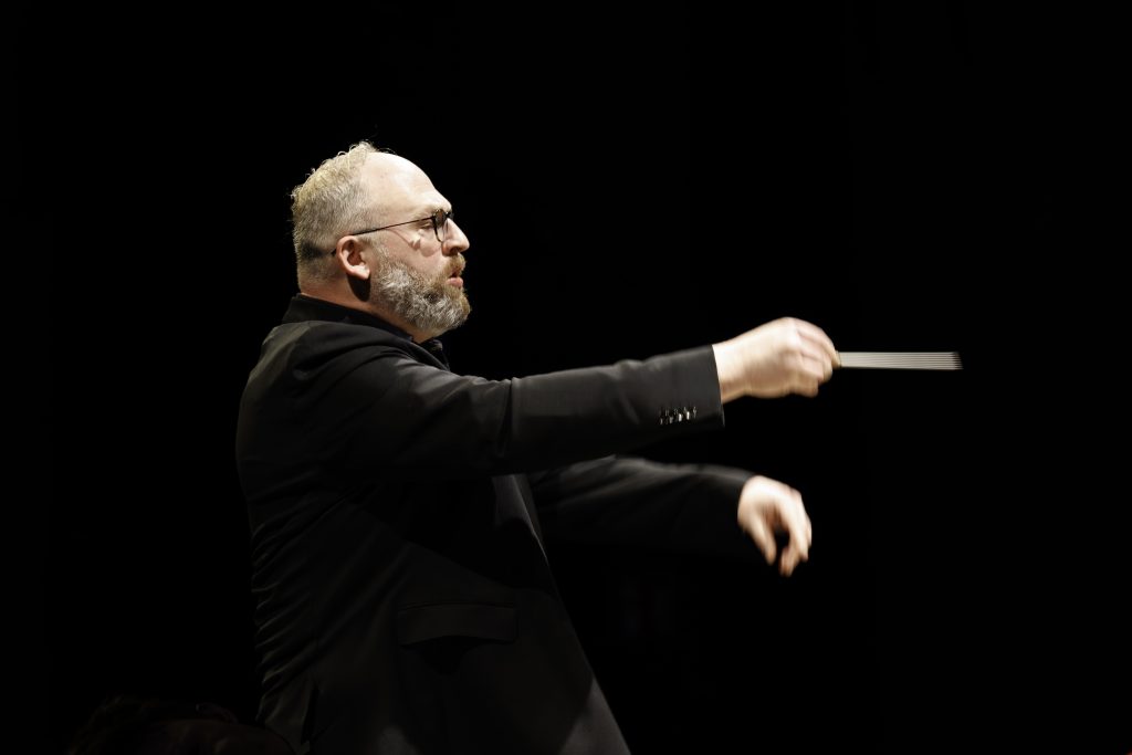 Dirigent in Aktion auf dunkler Bühne – Reportagefotograf Aschaffenburg bei Konzert