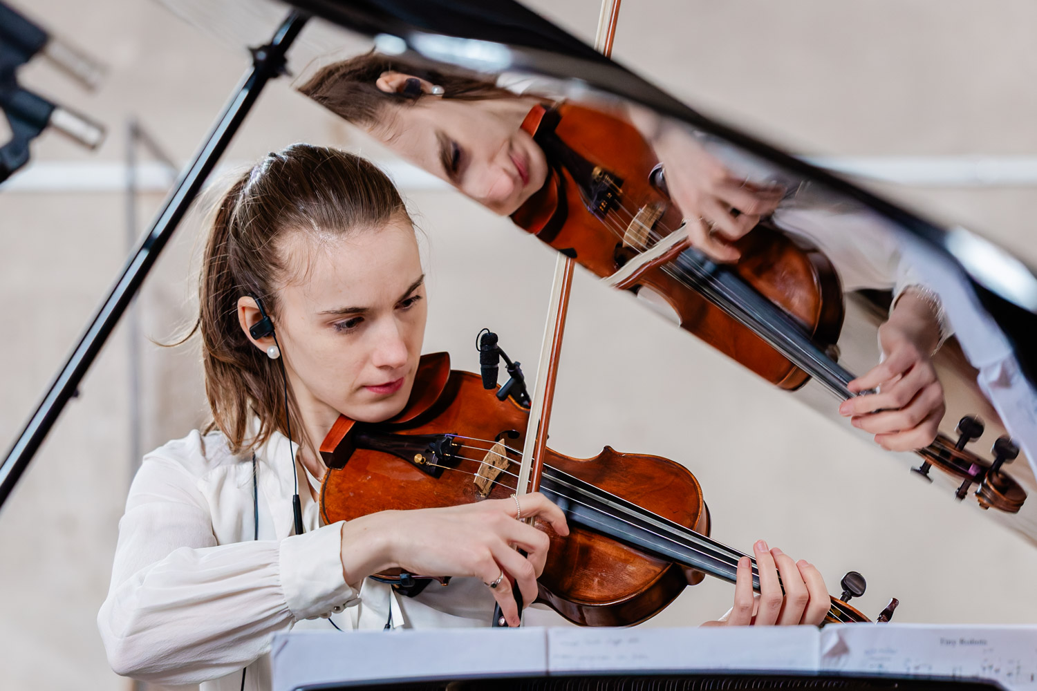 Reportagefoto: Geigerin spiegelt sich im Flügel bei Konzert in Aschaffenburg