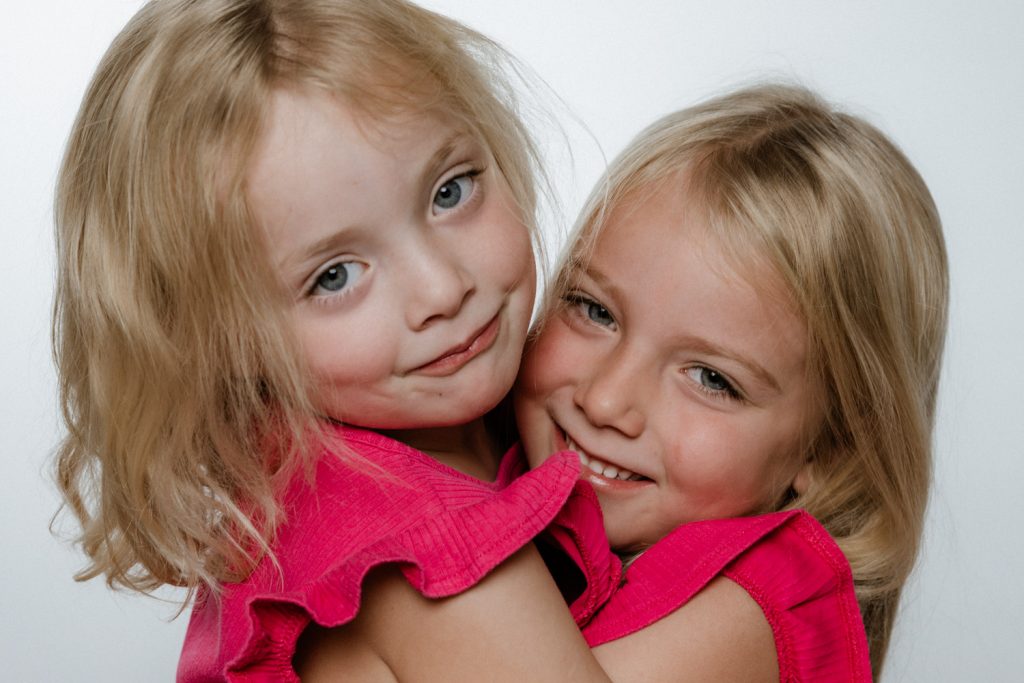 Zwei lachende Mädchen in pink vor weißem Hintergrund – Portraitfotograf Aschaffenburg