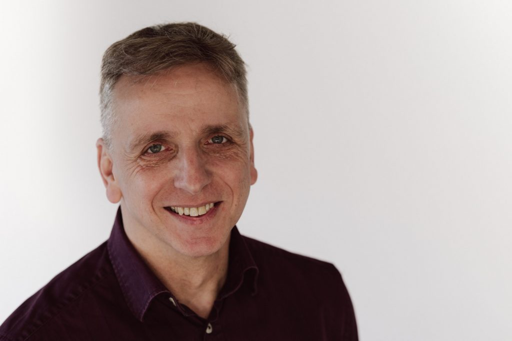 Business Fotograf Aschaffenburg, lächelnder Mann im Portrait vor hellem Hintergrund