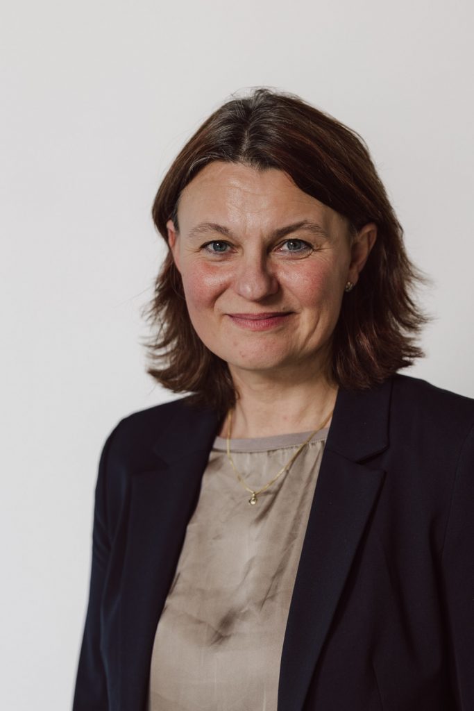 Businessportraits Aschaffenburg, Frau im Blazer mit freundlichem Ausdruck vor hellem Hintergrund